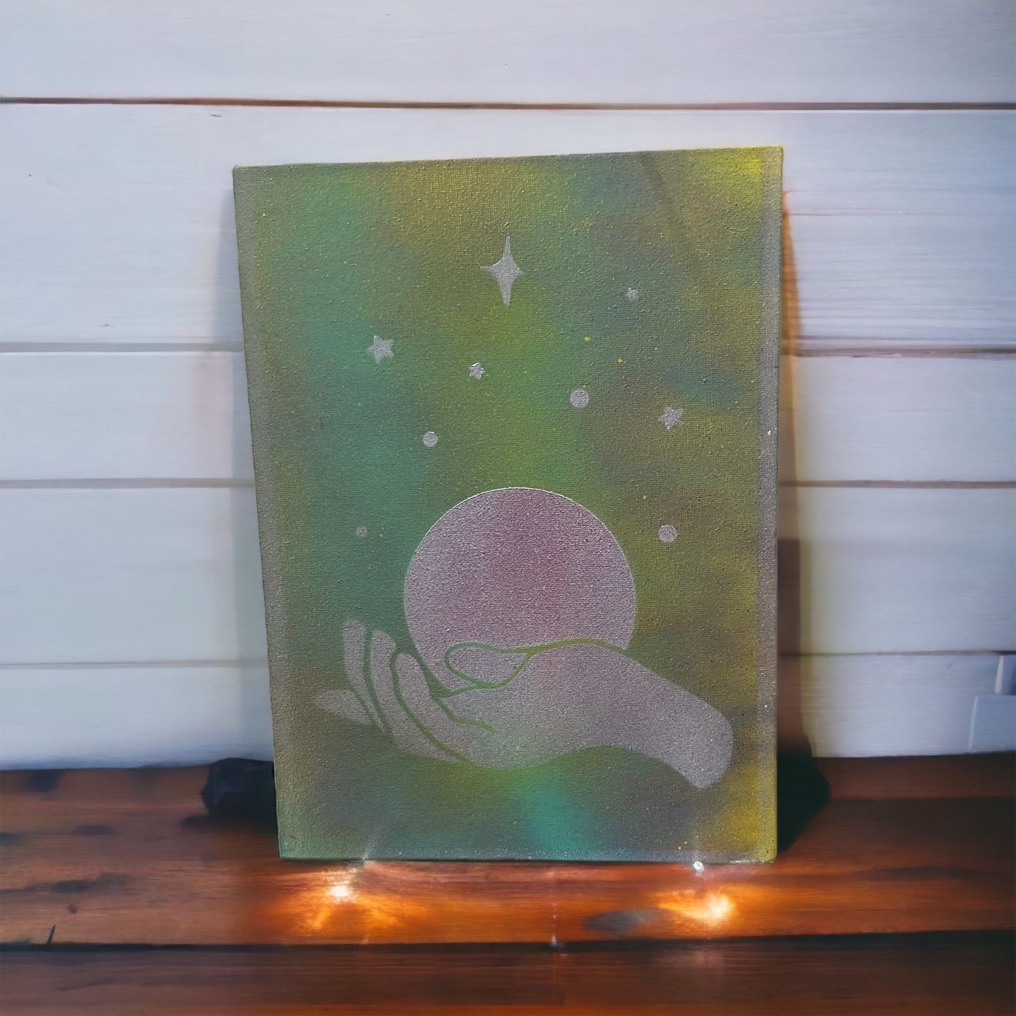 canvas painting of hand holding world and stars